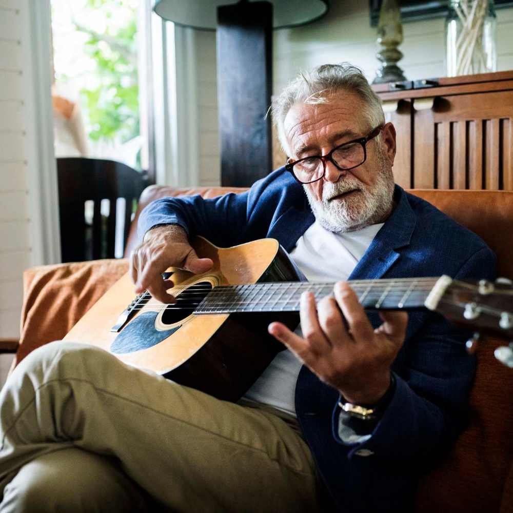 Senior man playing guitar in his living room at Crockett Manor Senior in Crockett, Texas