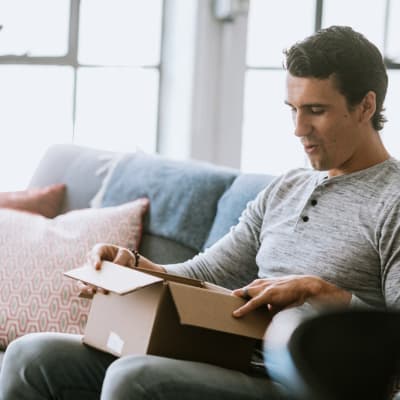 a resident opening a box on his couch at Heartwood in Joint Base Lewis McChord, Washington