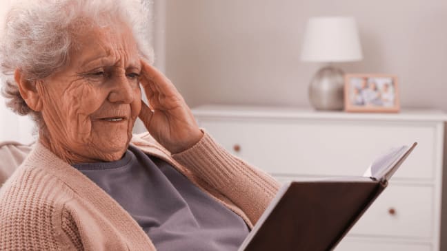 an old lady having a headache while reading something 
