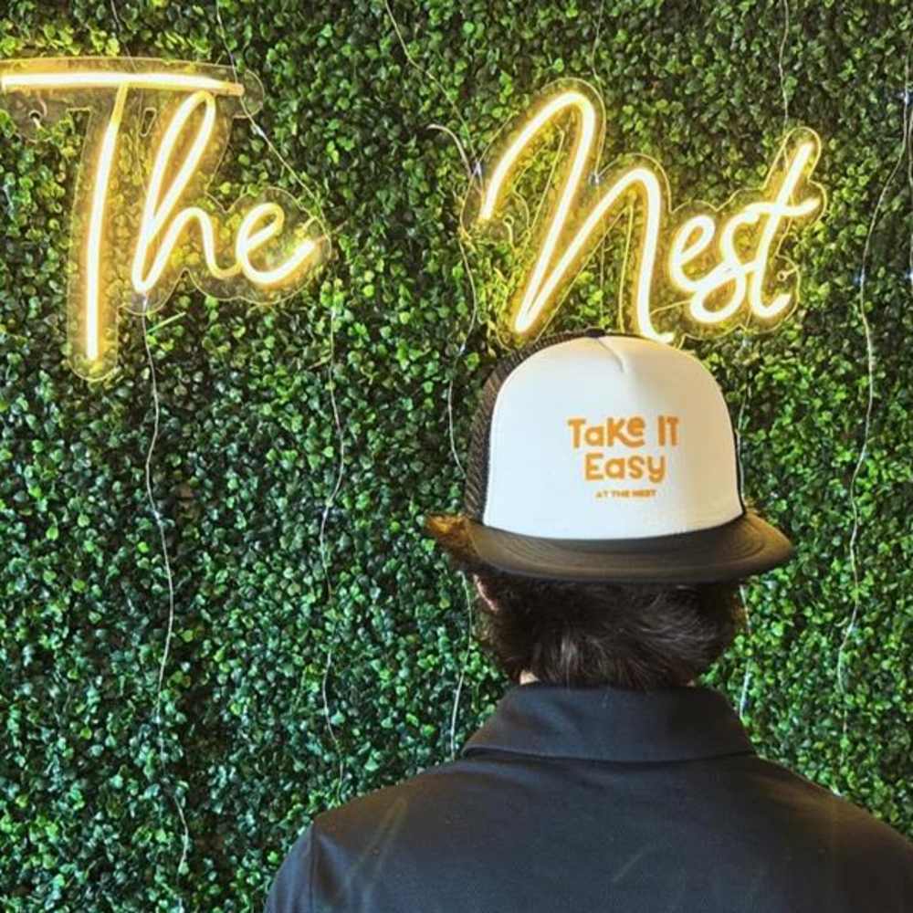 Resident standing near The Nest neon sign at The Nest in Iowa City, Iowa