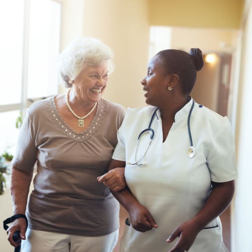 Onsite nurse walking down a hallway with a resident at Wesley Gardens in Montgomery, Alabama