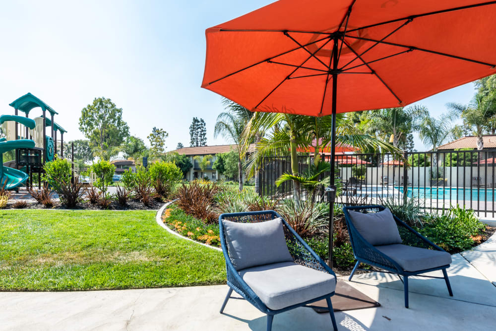 Patio seating under an umbrella by the pool and grilling station at Sofi Ventura in Ventura, California