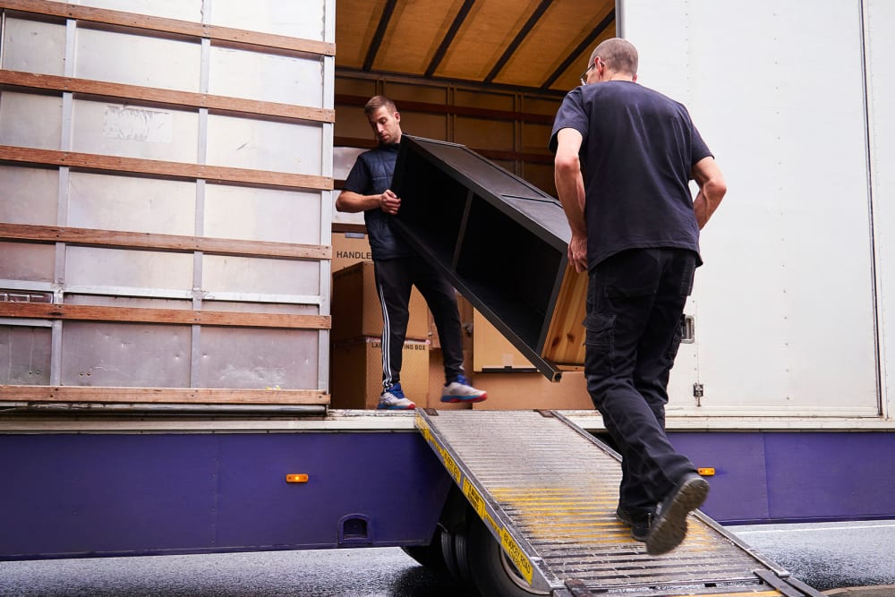 Two men loading furniture into a moving truck near A-American Self Storage