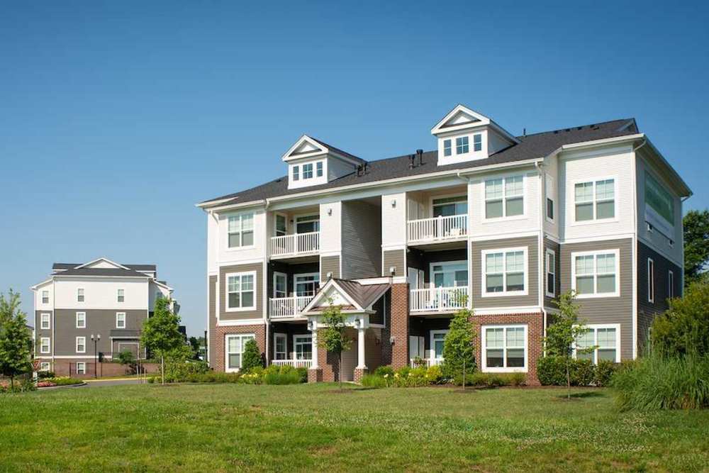 View of exterior of apartments and green lawn at The Elms at Signal Hill Station in Manassas, Virginia