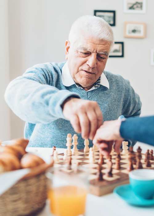 Caregiver playing chess with a resident at The Pineapple House at Sapphire Lakes in Naples, Florida
