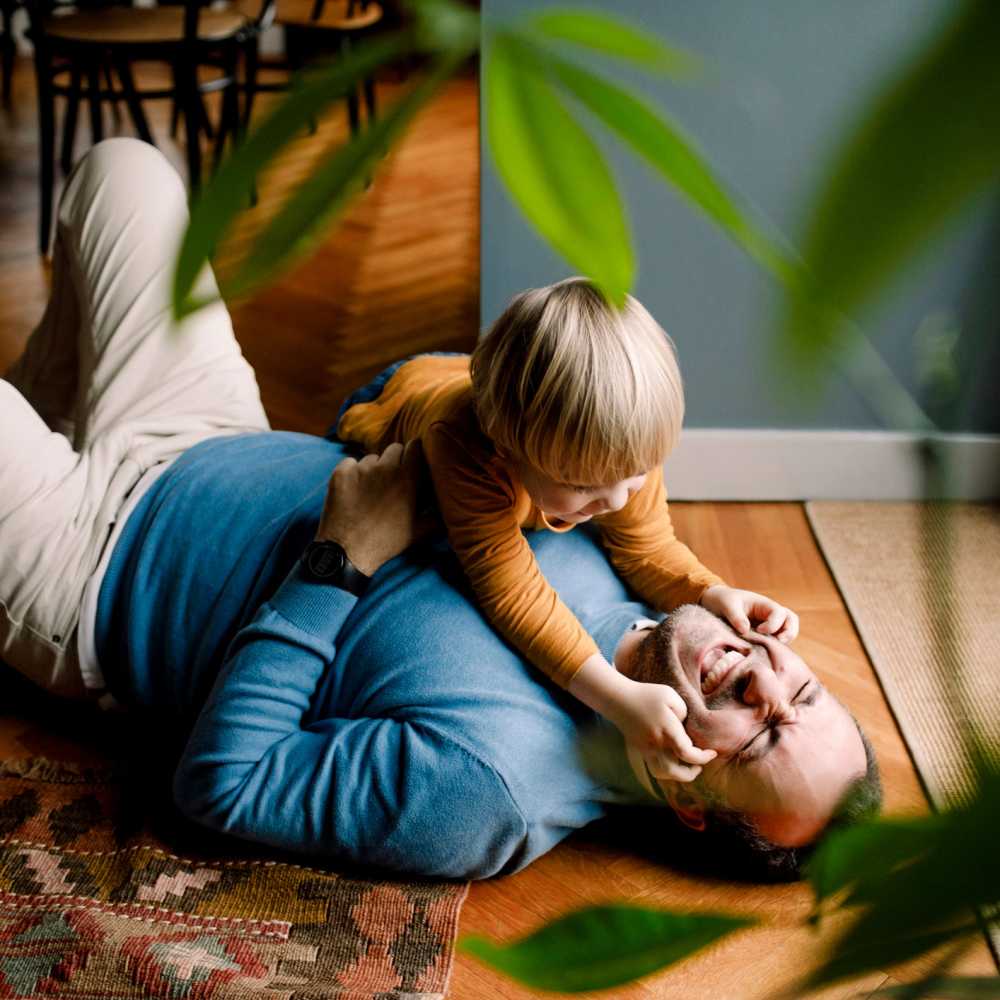 Father and son playing on the living room floor in their new apartment at Stadium Loft Apartments in Saint Louis, Missouri
