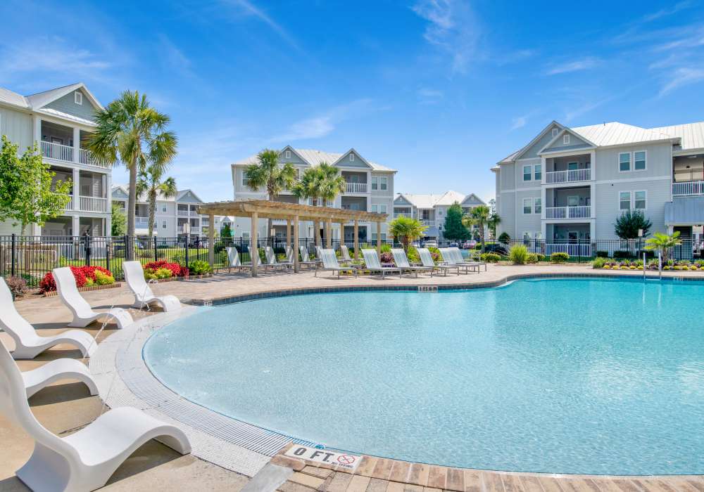 Resort-style swimming pool with relaxing chairs at The Crossings At Milestone in Pensacola, Florida