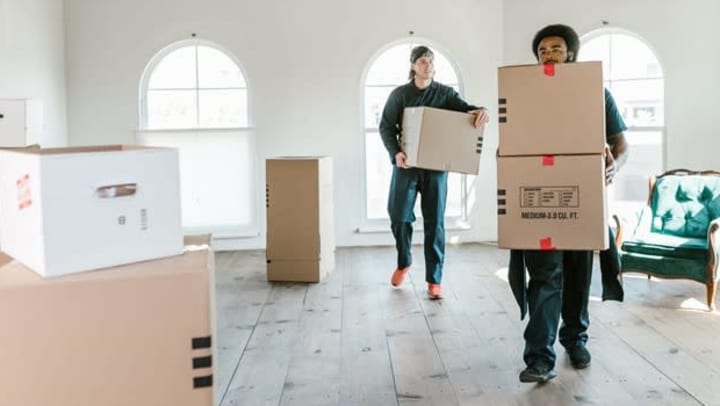 Two Professional Movers in the process of hauling moving boxes from a nice home | Photo by RODNAE Productions