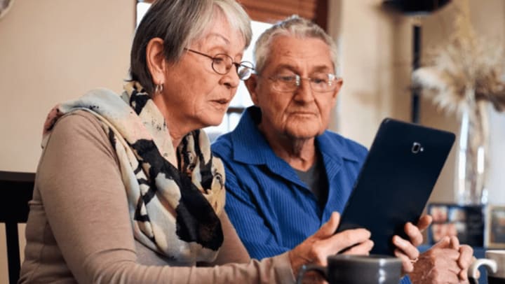 Two elderly adults looking at a tablet