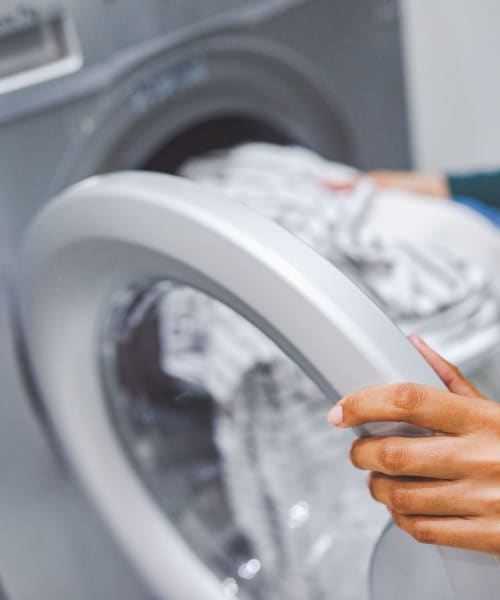 Person Loading Laundry into a Washing Machine at 1221 Vallejo Apartments in Novato, California