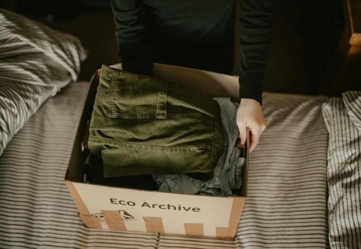 overhead view of a person packing clothing into a cardboard box