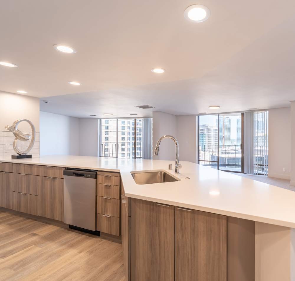 Modern kitchen with quartz countertops and rich, dark wood cabinetry in a model home at Tower 801 in Seattle, Washington