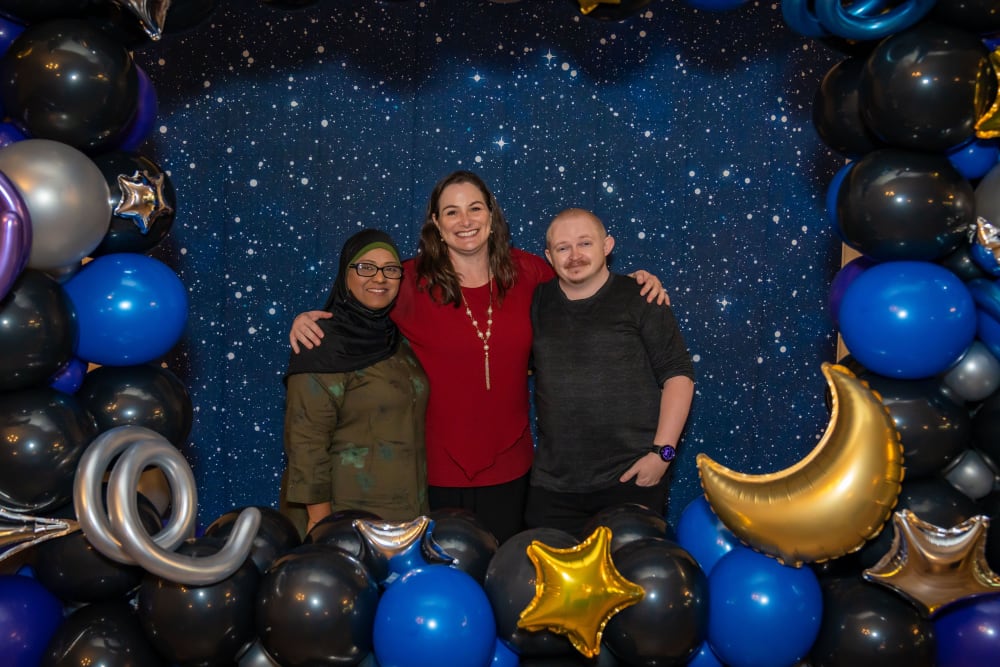 Three employees taking a picture with all of the event balloons around them at Ray Stone Inc.
