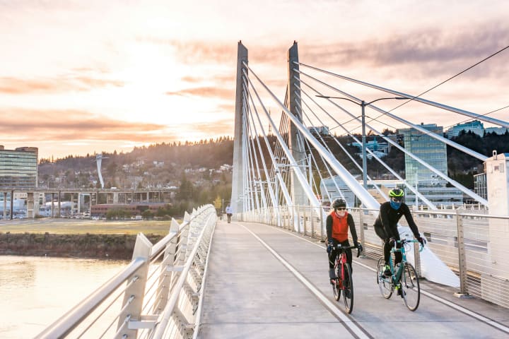 two cyclist ride bikes over a pedestrian bridge in Portland Oregon