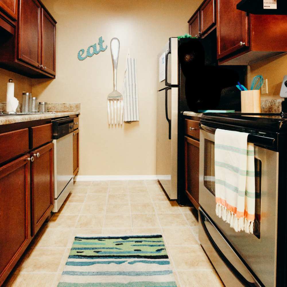 Fully equipped kitchen with granite countertops stainless steel appliances like a refrigerator, stove, and drawer microwave at Tapestry on Vaughn in Montgomery, Alabama