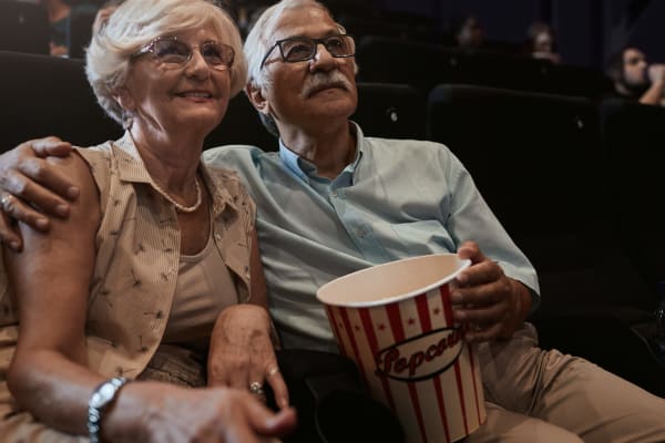 A couple watching a movie in a theatre eating popcorn