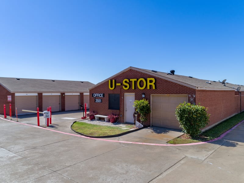 An exterior view of the office and storage units with blue doors at U-Stor Trinity Mills in Carrollton, Texas