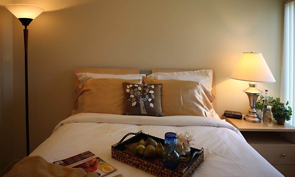 Comfortable bed in model home at Kensington Manor Apartments in Farmington, Michigan