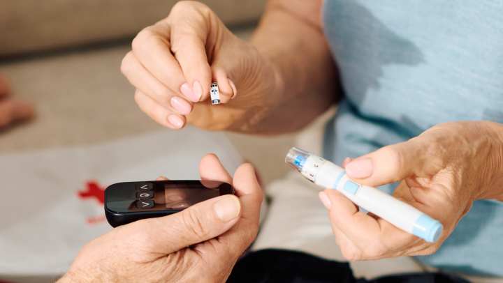 Senior diabetes care: An elderly couple managing blood sugar levels with a glucose meter and insulin pen at home.