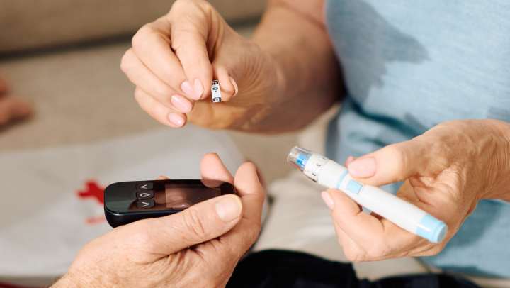 Senior diabetes care: An elderly couple managing blood sugar levels with a glucose meter and insulin pen at home.