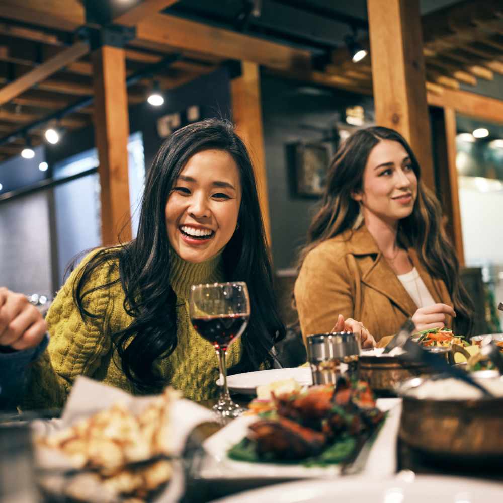 Resident friends sharing a laugh over a meal at their favorite restaurant near Erdace Apartments in Lake Charles, Louisiana