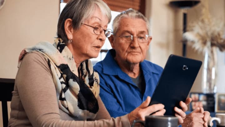 Two elderly adults looking at a tablet