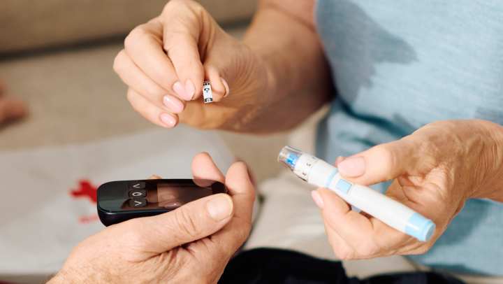 Senior diabetes care: An elderly couple managing blood sugar levels with a glucose meter and insulin pen at home.