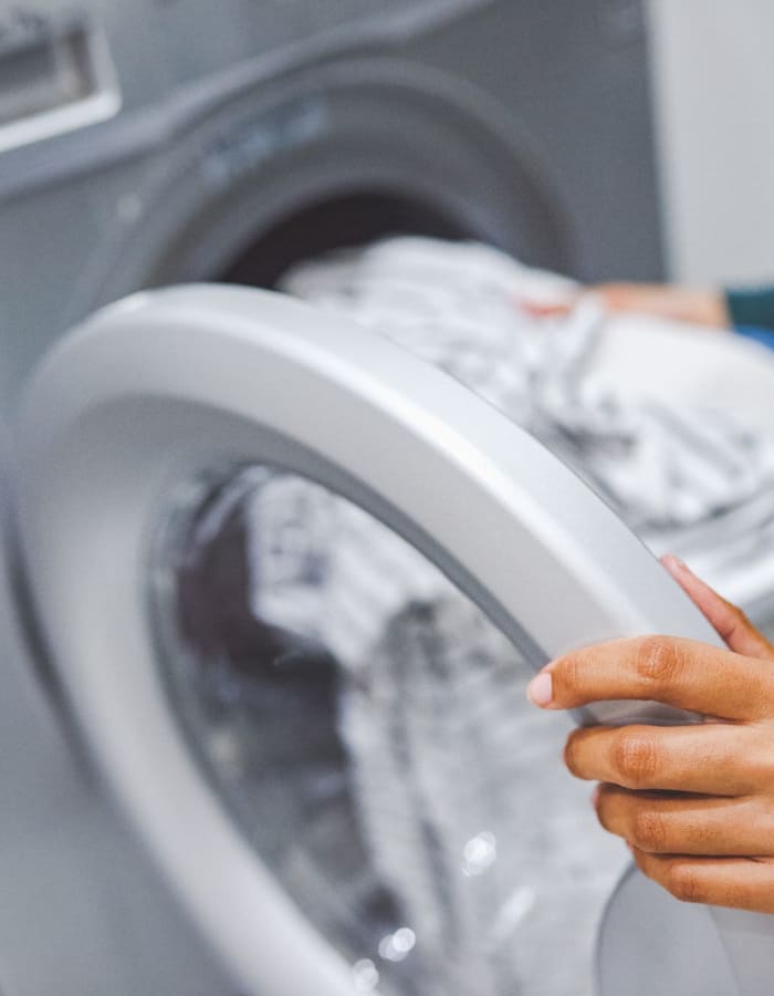 Close up of hands putting laundry into a washing machine at Vespaio in San Jose, California