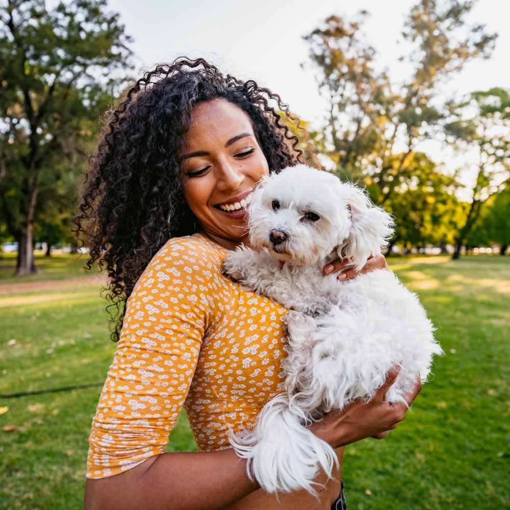 Resident smiling and holding her puppy outside on a beautiful day at Marlowe Place in Charlotte, North Carolina