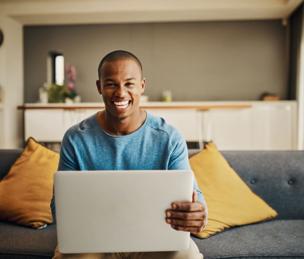 Resident student working on his computer at home on the couch of Virginia near Sofi 55 Hundred in Arlington, Virginia