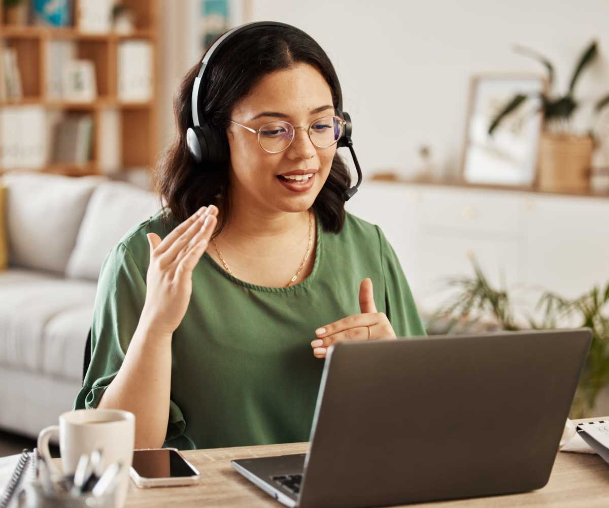 Resident wearing headset speaking while sitting at a desk with a laptop and coffee mug at Pando Aspen Grove in Indianapolis, Indiana