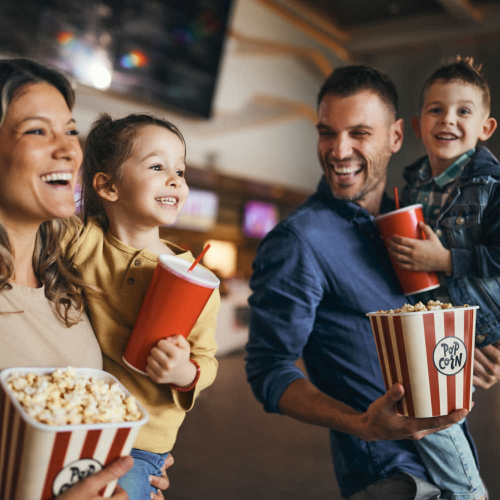 Smiling family holding popcorn and drinks at Avia Lofts at Maple Road in Amherst, New York