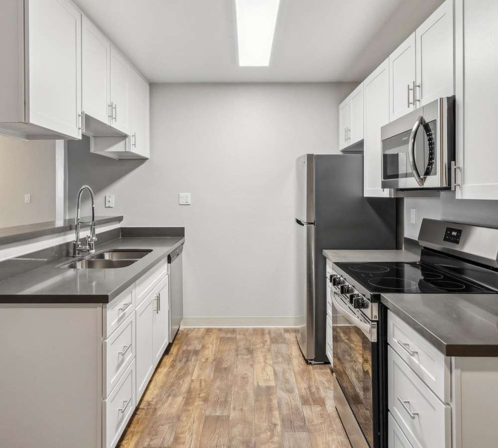 Kitchen with white cabinets, grey quartz countertops and stainless steel appliances