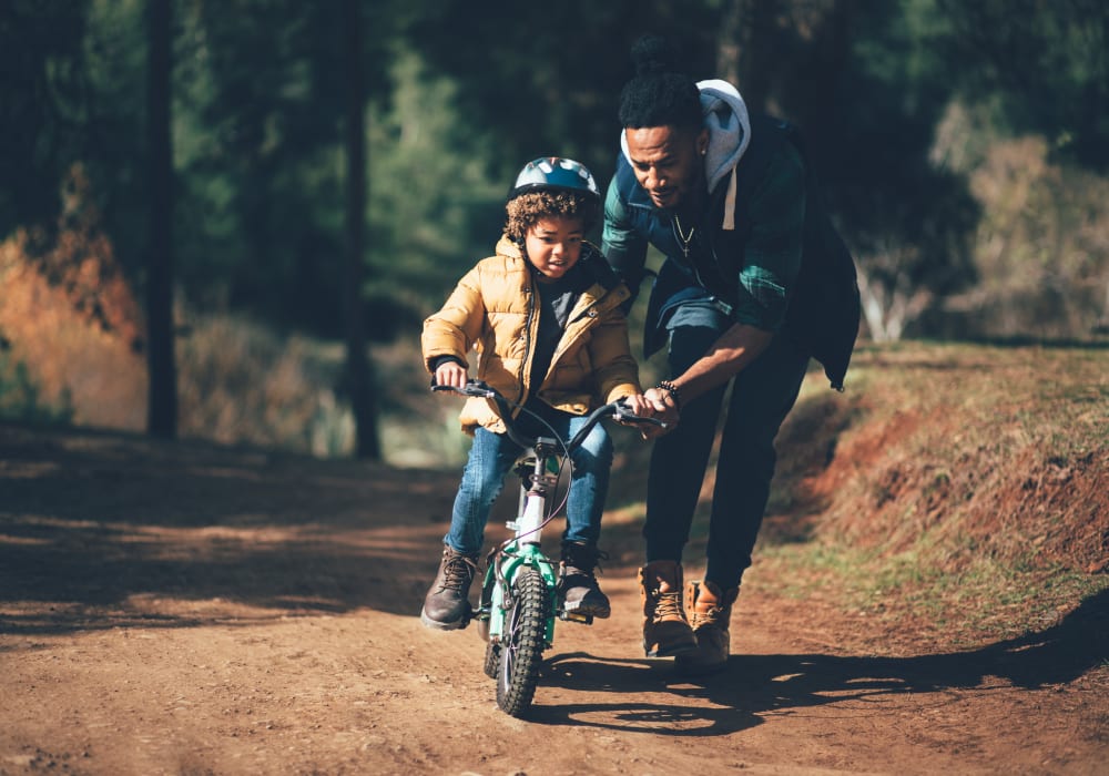 Father teaching his son how to ride a bike near The Trails at Canyon Crest in Riverside, California