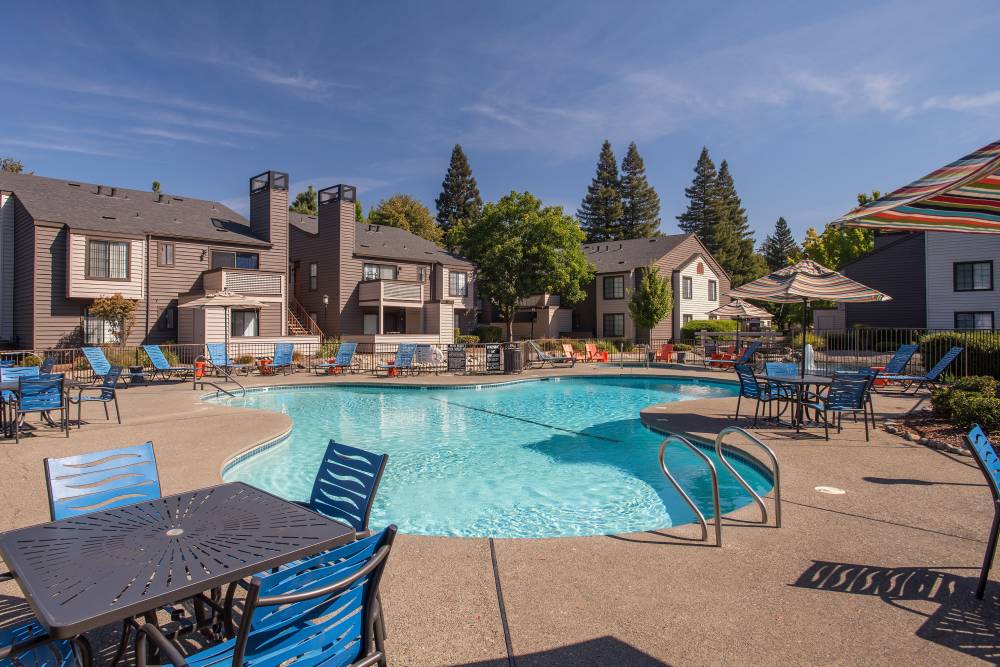 Spacious sundeck with table and chairs next to a swimming pool at Hidden Lake Condominium Rentals in Sacramento, California