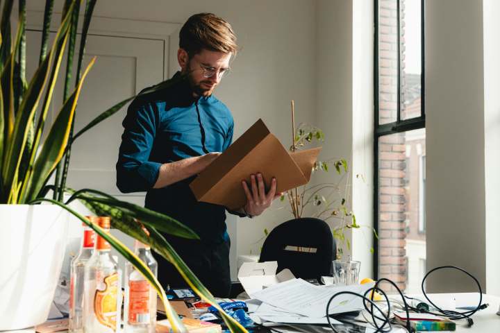 A person stands over a desk looking through file folders