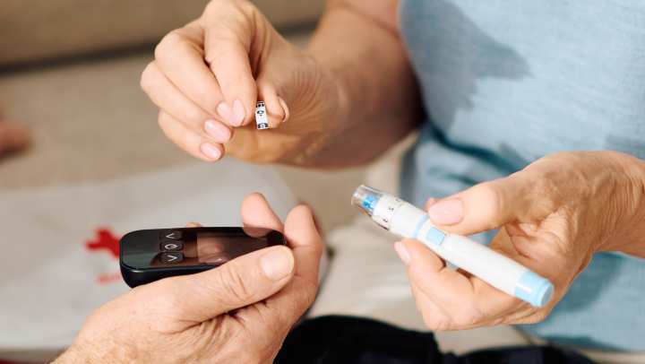 Senior diabetes care: An elderly couple managing blood sugar levels with a glucose meter and insulin pen at home.