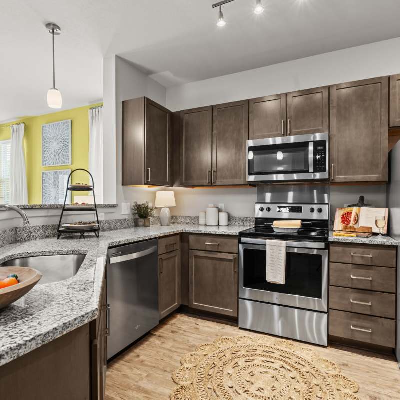 A kitchen with an island and granite countertop in a model luxury apartment at Pier Park Crossings in Panama City Beach, Florida