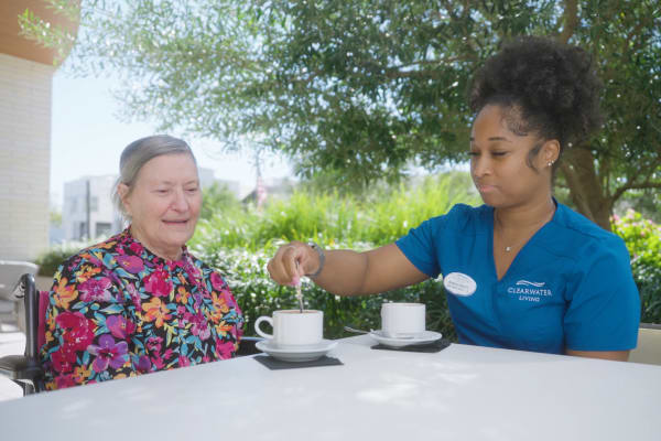 Caregiver and resident enjoying tea outside at Clearwater Newport Beach in Newport Beach, California