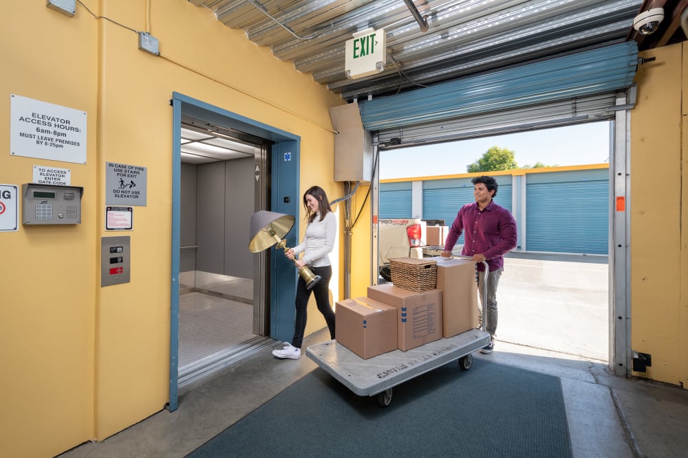 Couple with moving dolly walking into Hayward Storage LLC in Hayward, California