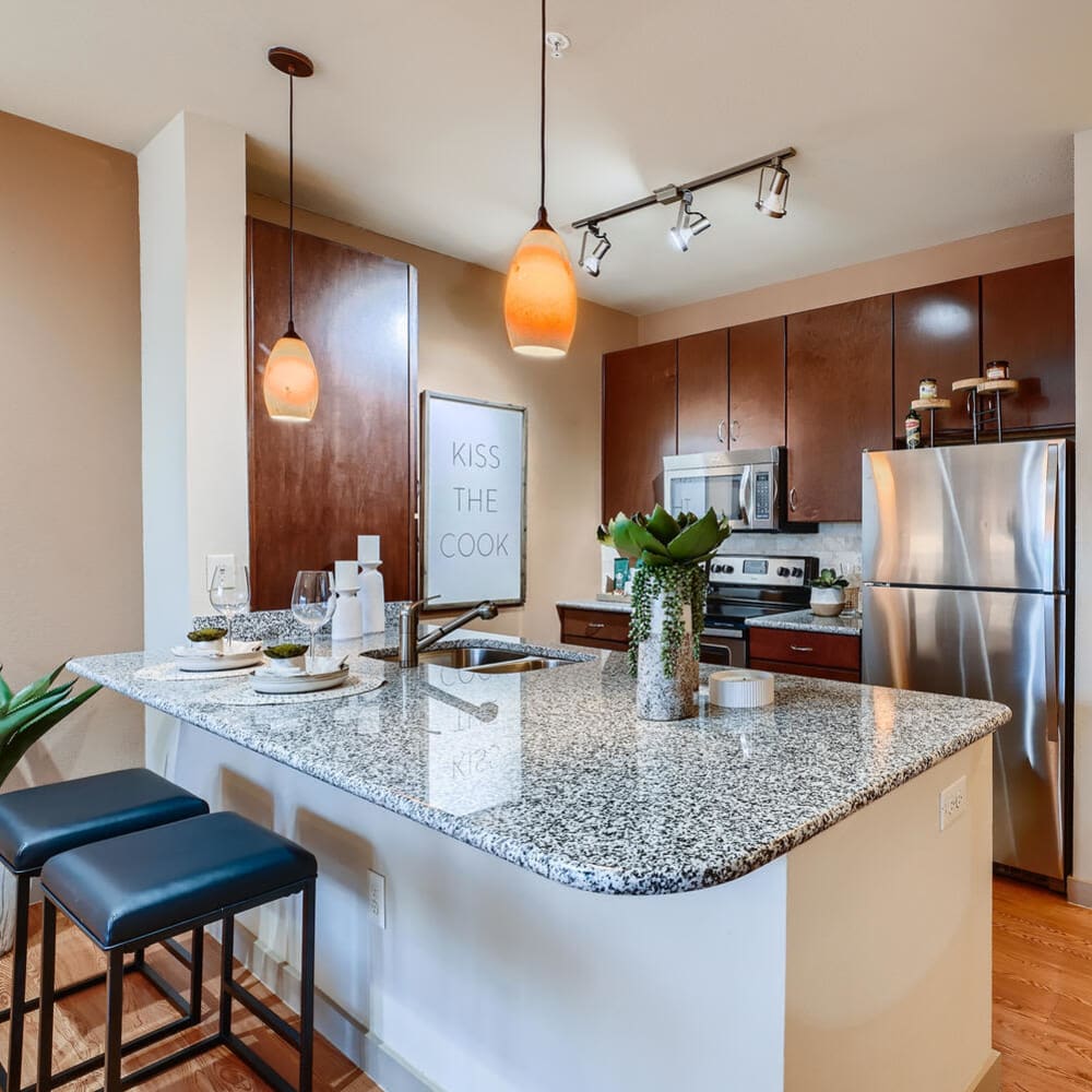 Beautiful modern kitchen with a breakfast bar, granite countertops, and pendant lighting at Imperial Lofts in Sugar Land, Texas