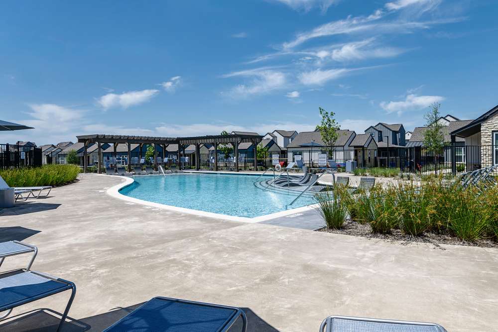 Resort-infused pool with tanning deck and pool loungers at parcHAUS AT CELINA PARKWAY in Celina, Texas