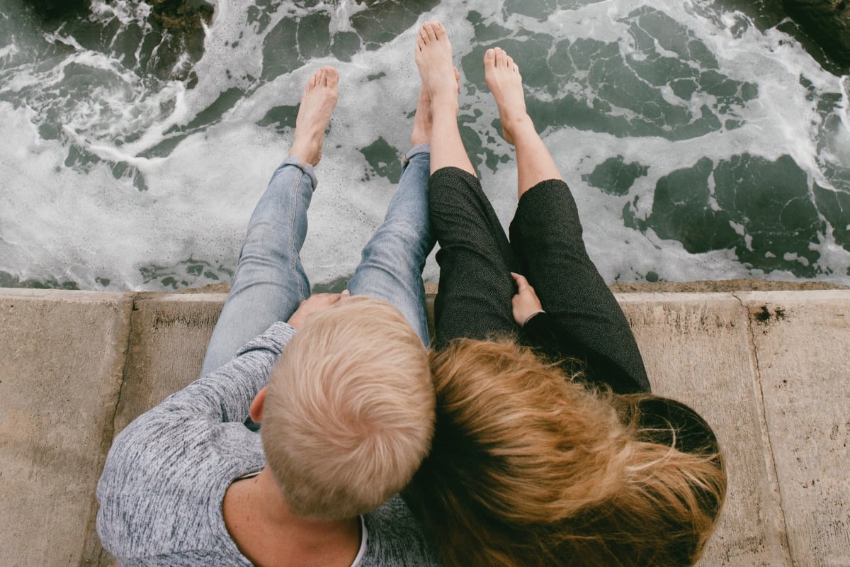 A couple dangling their legs over the ocean near The Villas at Anacapa Canyon in Camarillo, California
