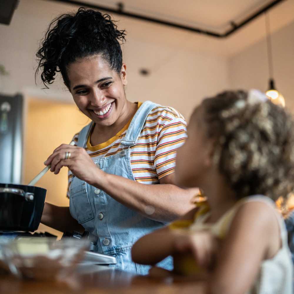 Mother and daughter cooking and enjoying their new space together in their apartment home at Central West End Apartments in Saint Louis, Missouri