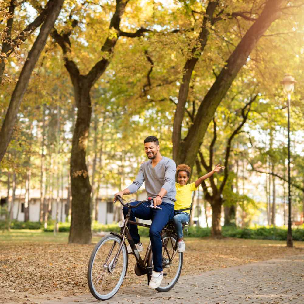 Man riding bike with his child at Stadium West Apartments in Arlington,Texas