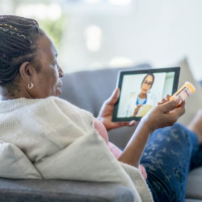 Resident discussing her care plan with a doctor via teleconference on a tablet device at Cascade Park Gardens Memory Care in Tacoma, Washington