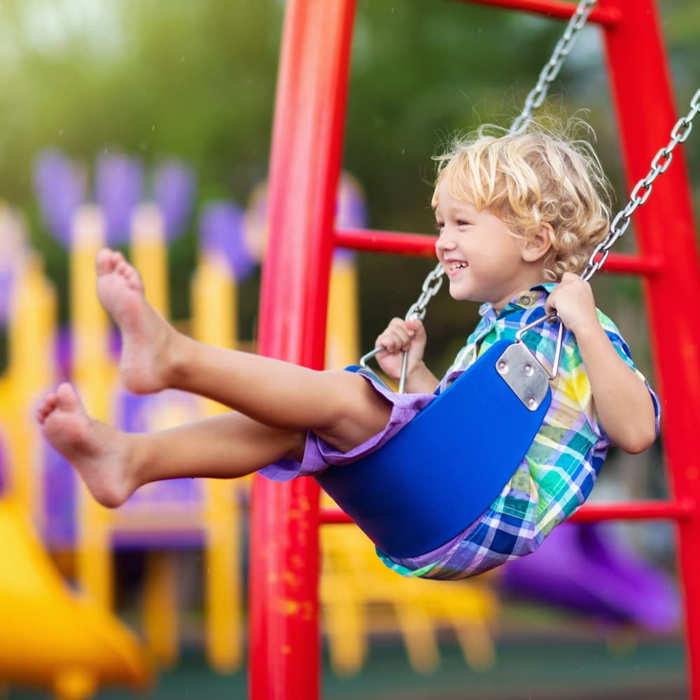 Child playing on swing with a smile near Groves at Peach Orchard in Belmont, North Carolina