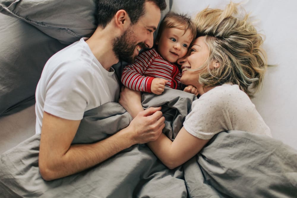 Couple snuggling with their baby in bed in their luxury home at Sanctuary on 51st in Laveen, Arizona