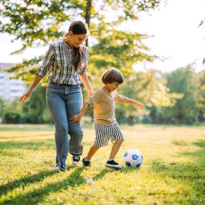 Resident with her kid playing football in a park at The Heights at Waterpointe in Flowood, Mississippi
