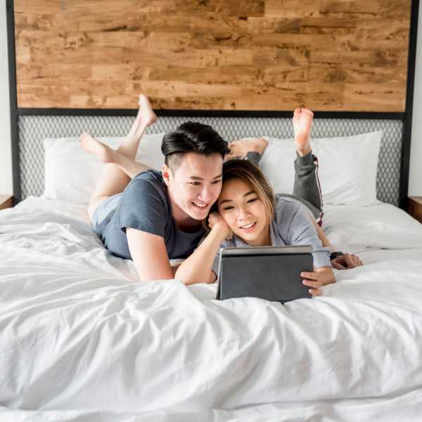 Happy couple watching iPad in bedroom at Detroit Living in Detroit, Michigan